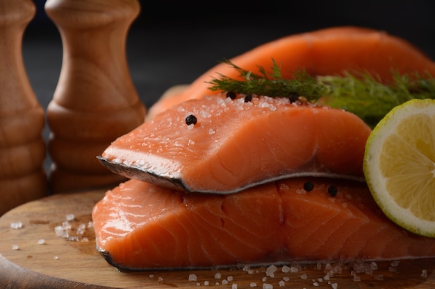 Filete de pescado de salmón crudo fresco con ingredientes de cocina hierbas y limón sobre fondo negro