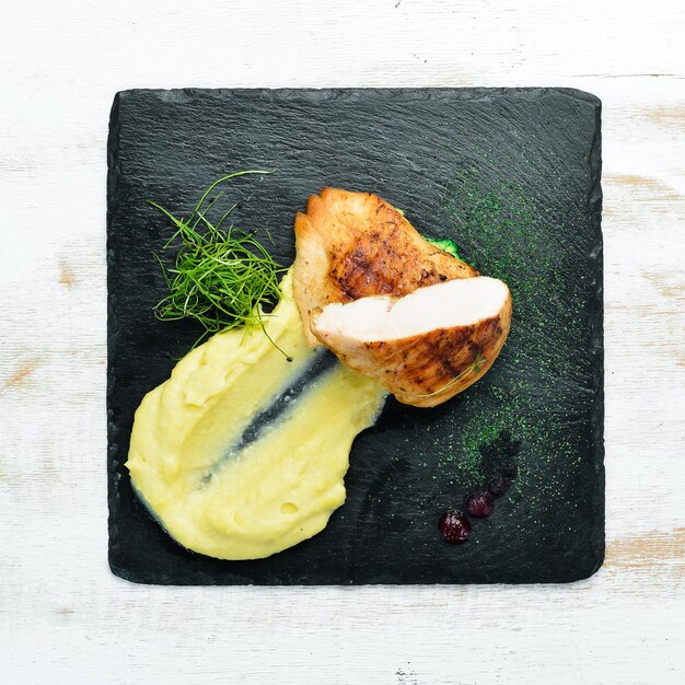 Filete de pollo al horno con puré de papas en un plato de piedra negra Vista superior espacio libre para su texto Estilo rústico