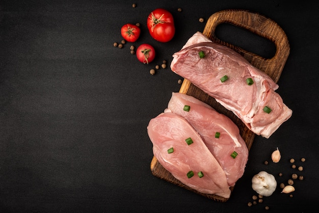 Filete de pollo crudo y carne de cerdo en un cuadro negro