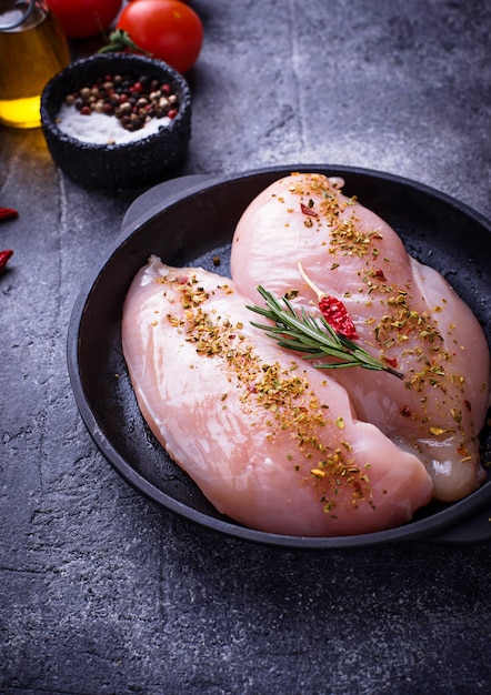 Filete de pollo crudo en sartén de hierro fundido