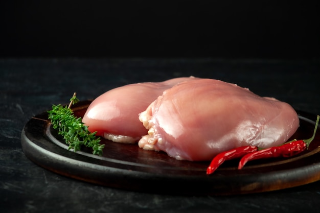 Filete de pollo crudo sobre tabla de madera