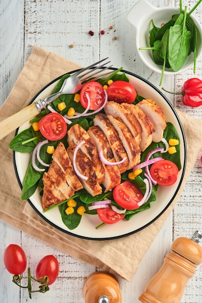 Filete de pollo con ensalada de espinacas, tomates cherry, aciano y cebolla. Comida sana. Dieta cetogénica, concepto de almuerzo de dieta. Vista superior sobre fondo blanco.