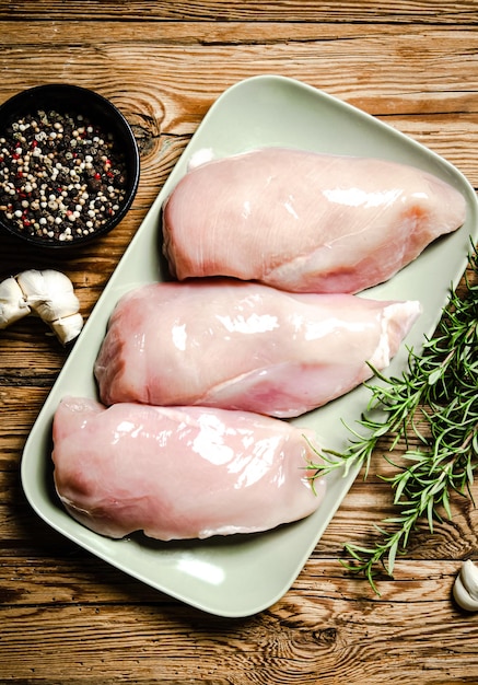 Filete de pollo fresco con especias en una mesa de madera