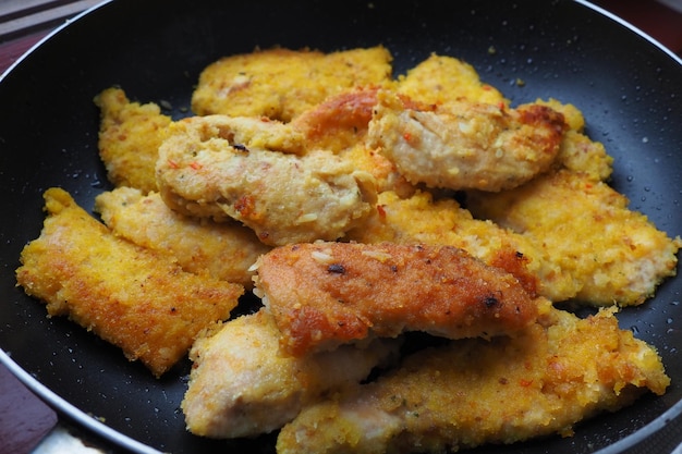 Filete de pollo frito en un primer plano de sartén negro Muchas piezas de pollo frito enrolladas en pan rallado Recetas caseras rápidas para cocinar y procesar el cuerpo de productos cárnicos