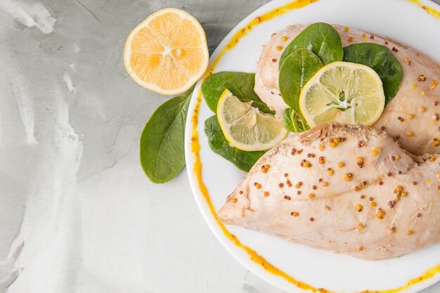 Filete de pollo hervido con mostaza y primer plano de limón