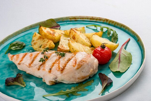 Filete de pollo a la parrilla con patatas fritas sobre fondo claro