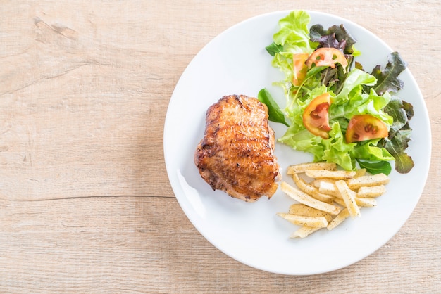 Foto filete de pollo a la plancha con papas fritas y ensalada de verduras