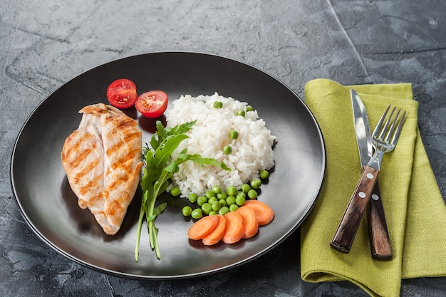 Filete de pollo a la plancha en un plato con arroz hervido y verduras