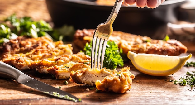 Filete de pollo vienés en un tenedor. Plato tradicional austriaco y alemán de carne de pollo y pan rallado.