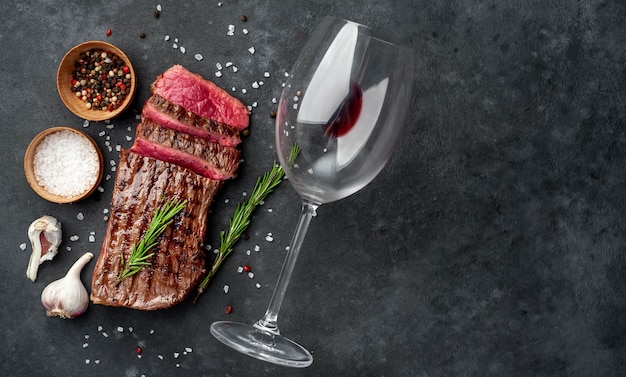 Filete de res a la parrilla con especias y una copa de vino sobre un fondo de piedra