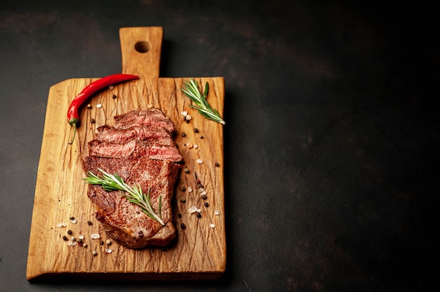 Filete de res a la parrilla sobre una tabla de cortar con especias sobre un fondo de piedra con espacio de copia para su texto