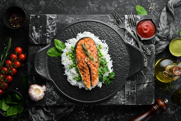 Filete de salmón al horno con arroz y verduras en un plato de piedra negra Mariscos Vista superior Espacio libre para su texto