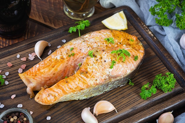 Filete de salmón al horno con hierbas sobre tabla de cortar de madera Salmón a la parrilla con sal y pimienta