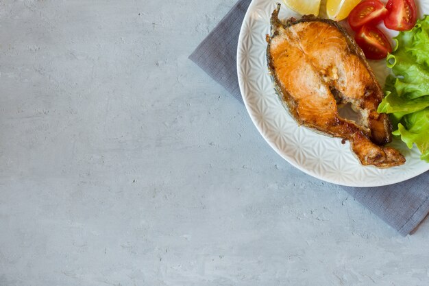 Filete de salmón al horno pescado en un plato con verduras frescas.