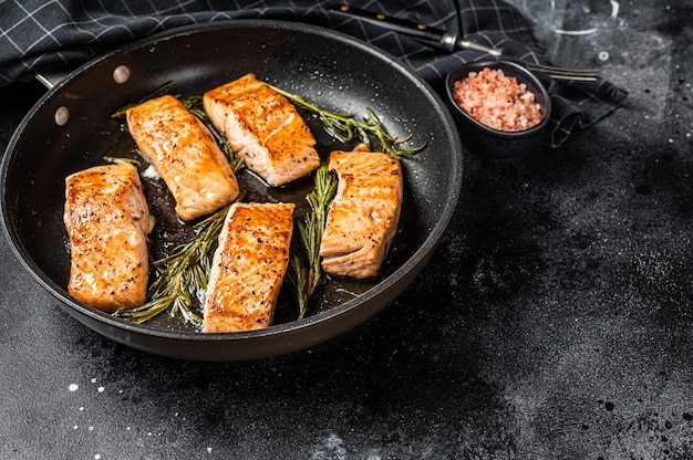 Foto filete de salmón asado en una sartén con romero