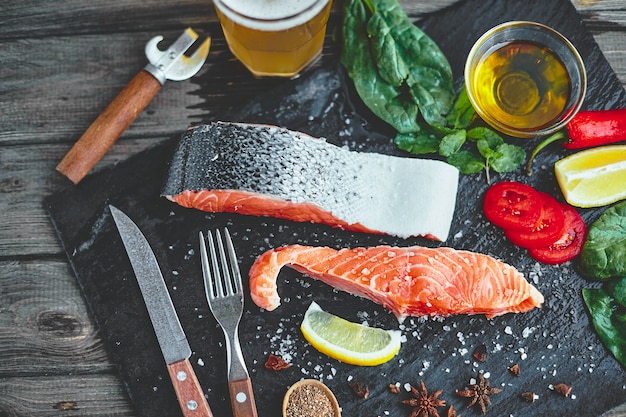 Filete de salmón crudo e ingredientes para cocinar en una mesa oscura