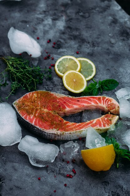 Filete de salmón crudo con hielo de hierbas y limón sobre fondo gris