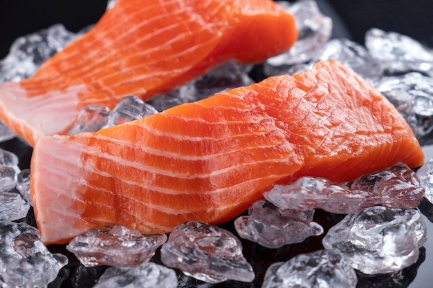 Filete de salmón crudo en hielo en superficie oscura. De cerca