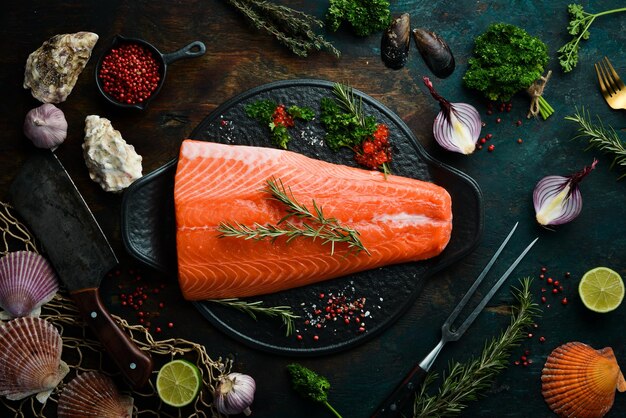 Filete de salmón crudo con romero en un plato de piedra negra Sobre un fondo oscuro Lay Flat