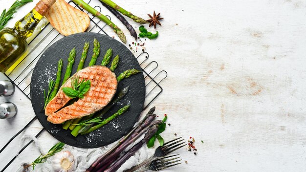 Filete de salmón con espárragos al horno y especias en un plato de piedra negra Vista superior Espacio libre para el texto