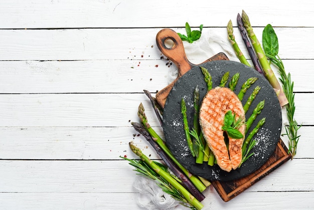 Filete de salmón con espárragos al horno y especias en un plato de piedra negra Vista superior Espacio libre para el texto