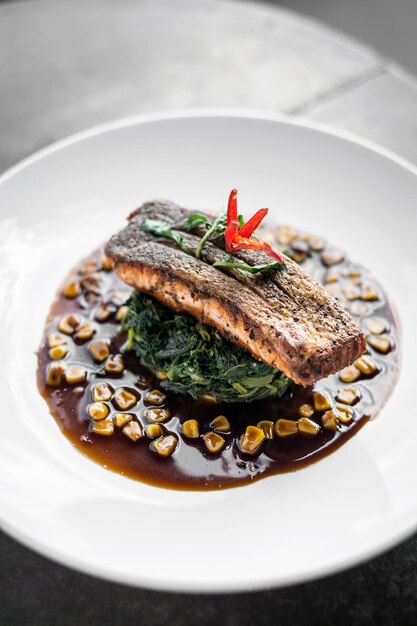 Foto filete de salmón con espinaca al vapor y maíz con salsa de soja