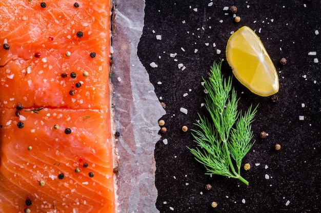 Filete de salmón fresco con eneldo y limón sobre fondo oscuro