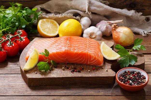 Filete de salmón fresco con ingredientes para cocinar en una tabla de madera, vista superior