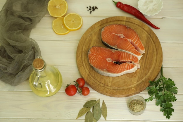 Filete de salmón fresco con ingredientes sobre fondo blanco de madera