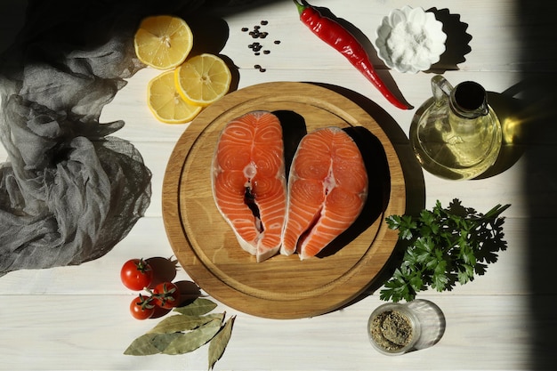 Filete de salmón fresco con ingredientes sobre fondo blanco de madera