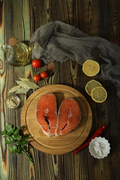 Filete de salmón fresco con ingredientes sobre fondo de madera oscura.