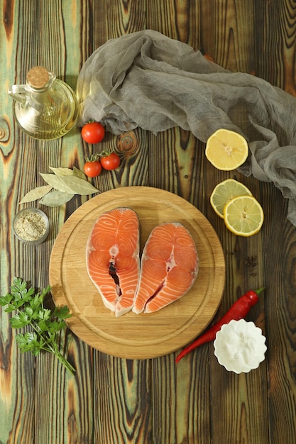 Filete de salmón fresco con ingredientes sobre fondo de madera oscura.