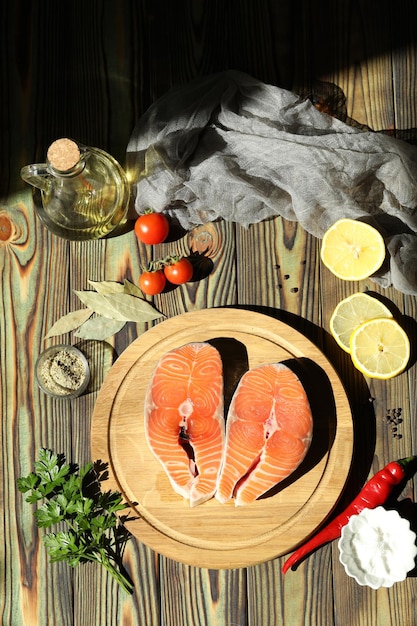 Filete de salmón fresco con ingredientes sobre fondo de madera oscura.