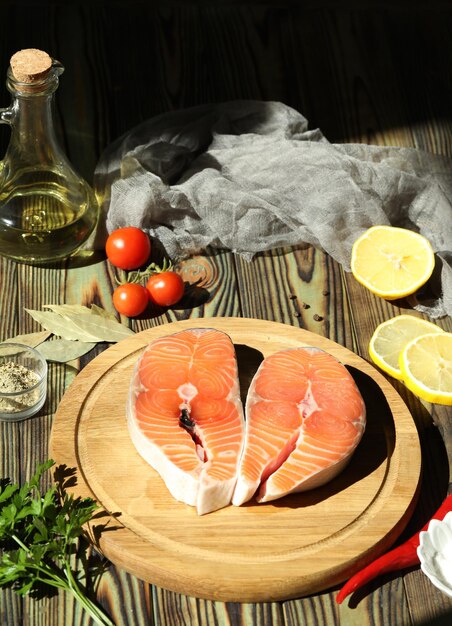 Filete de salmón fresco con ingredientes sobre fondo de madera oscura.