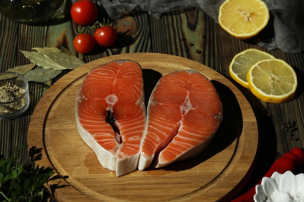 Filete de salmón fresco con ingredientes sobre fondo de madera oscura.