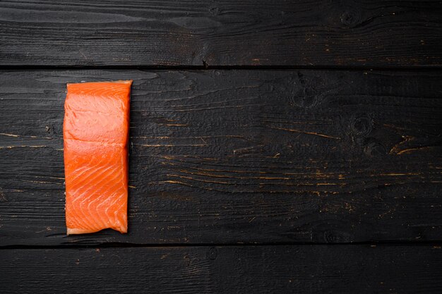 Filete de salmón fresco, sobre fondo de mesa de madera negra, vista superior plana, con espacio para copiar texto