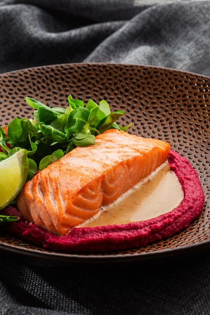 Filete de salmón frito con guarnición de humus rosa.