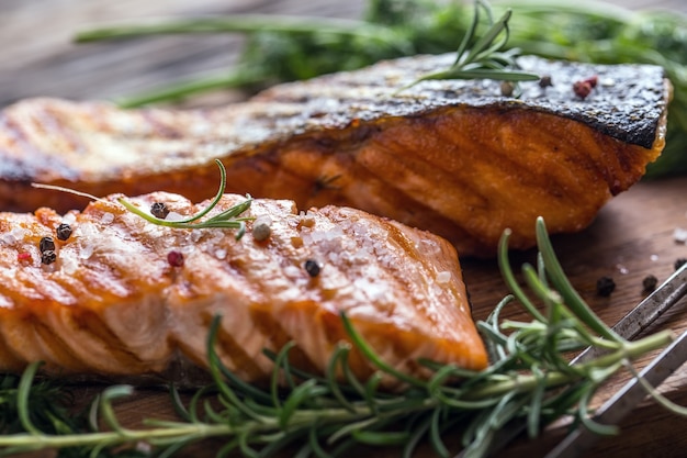 Filete de salmón a la parrilla, semillas de sésamo, decoración de hierbas en sartén vintage o tablero de pizarra negra