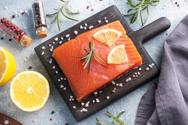 Filete de salmón, pescado rojo salado sobre una tabla de cortar de madera. Especias de limón, romero.
