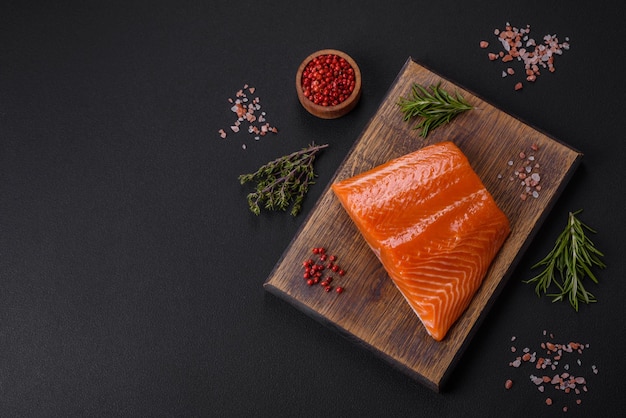 Filete de salmón rojo crudo con especias saladas y hierbas sobre un fondo de hormigón oscuro