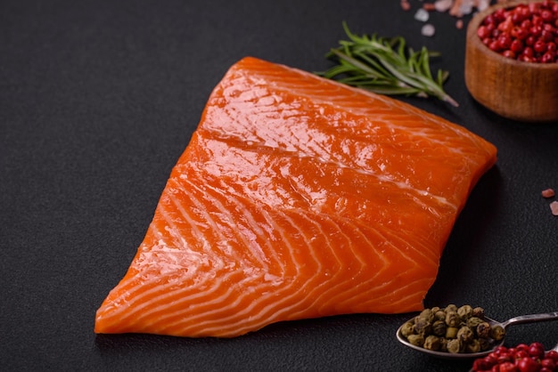 Filete de salmón rojo crudo con especias saladas y hierbas sobre un fondo de hormigón oscuro