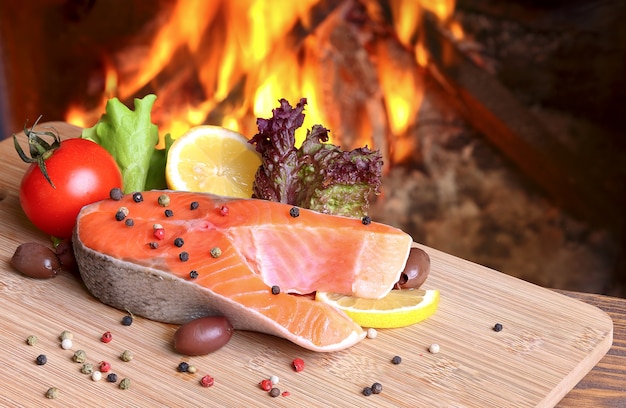 Filete de salmón sobre una tabla de cortar sobre un fondo de una llama ardiente