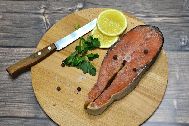 filete de salmón en la tabla de cortar con un cuchillo de rodajas de limón y espacio para copiar sal rosa