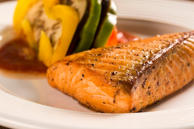 Filete de salmón con verduras mixtas sobre superficie de madera