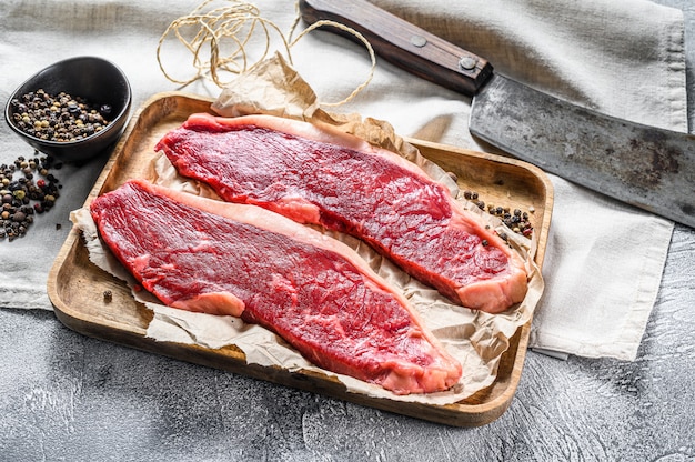 Filete de solomillo crudo en una bandeja de madera con una cuchilla de carne. Mármol de res. Fondo gris Vista superior