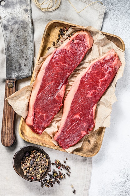 Filete de solomillo crudo en una bandeja de madera con una cuchilla de carne. Mármol de res. Superficie gris. Vista superior