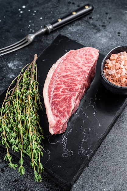 Filete de solomillo crudo wagyu, carne de res de kobe en tablero de mármol. Fondo negro. Vista superior.