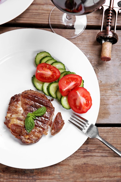 Filete de ternera asado y verduras frescas en un plato sobre fondo de madera