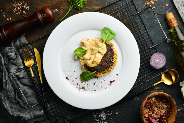 Filete de ternera con bulgur y champiñones en un plato. Menú del restaurante. cocina europea.