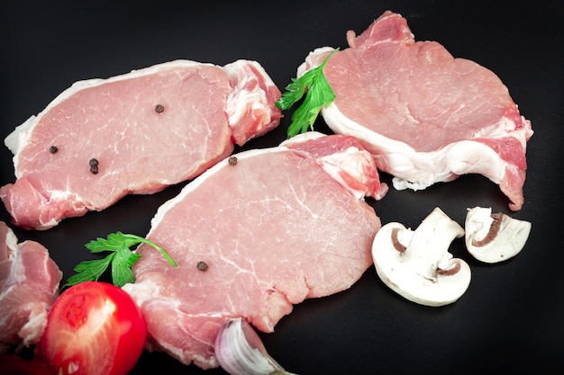 Filete de ternera de carne cruda sobre fondo oscuro con ingredientes para cocinar